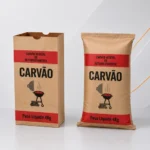 Dois sacos de papel kraft para carvão vegetal de 4 kg, um com fundo colado e outro com fundo costurado, apresentados em fundo clean de estúdio nas cores branco, cinza e prata.