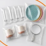Sacos de plástico bolha transparentes protegendo copos, pratos de cerâmica, xícaras e espelho, demonstrando a embalagem ideal para transporte e armazenamento seguro de produtos frágeis.