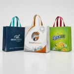 Três sacolas de ráfia laminada personalizadas com impressão de alta qualidade para empresas, alinhadas em estúdio sobre fundo branco, representando embalagens promocionais reutilizáveis para ações de marketing e eventos corporativos.