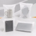 Sacos de polietileno expandido (EPE) protegendo uma caneca de cerâmica, um espelho de mesa, um caderno espiral e um notebook, demonstrando a proteção contra riscos e impactos.
