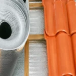 Manta térmica aluminizada refletiva em rolo instalada sob telhado de cerâmica, utilizada para isolamento térmico e conforto em coberturas residenciais e comerciais.