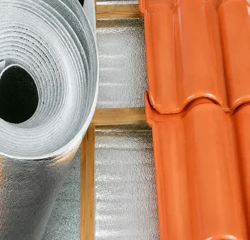 Manta térmica aluminizada refletiva em rolo instalada sob telhado de cerâmica, utilizada para isolamento térmico e conforto em coberturas residenciais e comerciais.